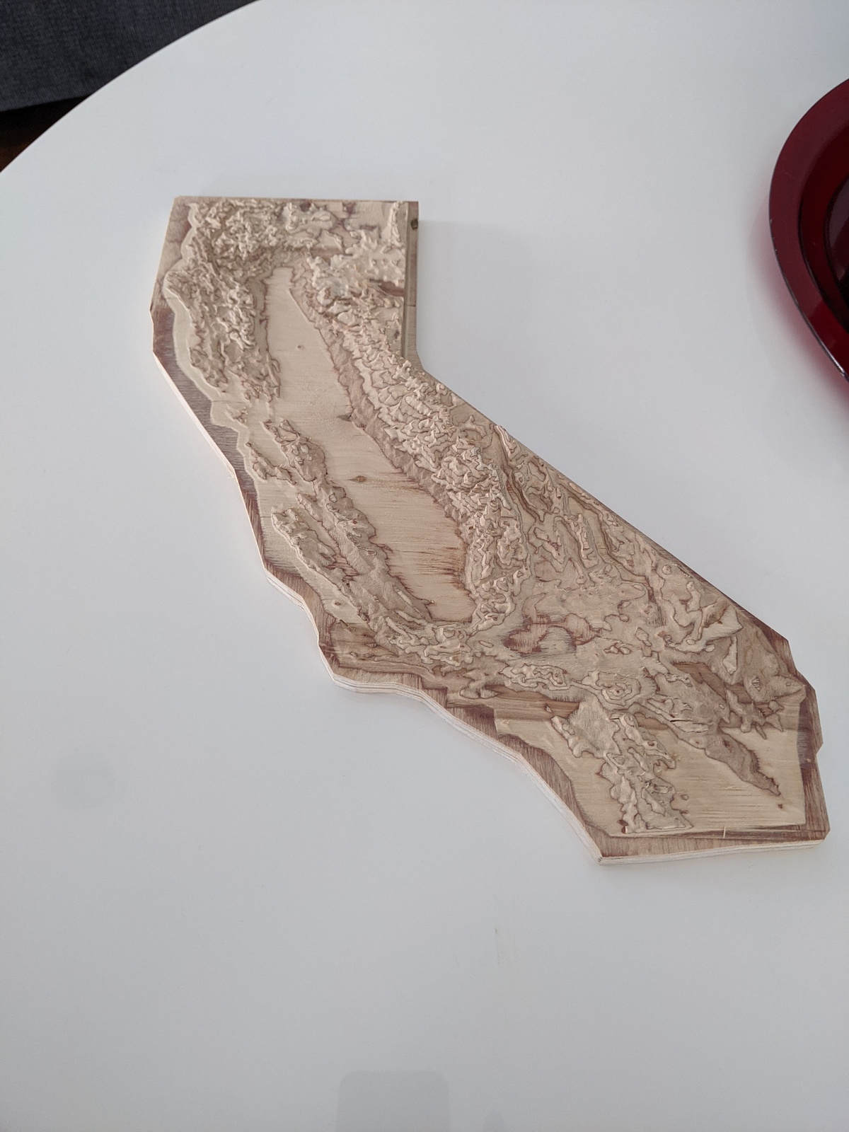 A plywood slab carved with CNC into a topographic representation of California
